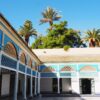 the courtyard of a building with palm trees in the background