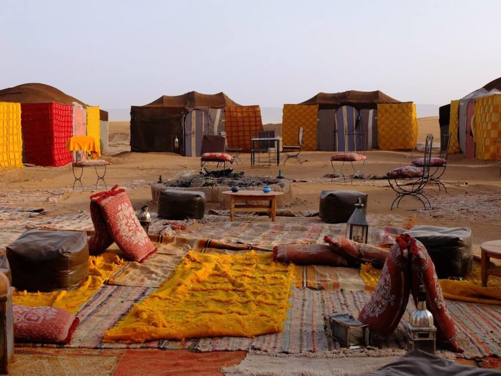 Salon extérieur avec coussins et tapis colorés dans un campement du désert