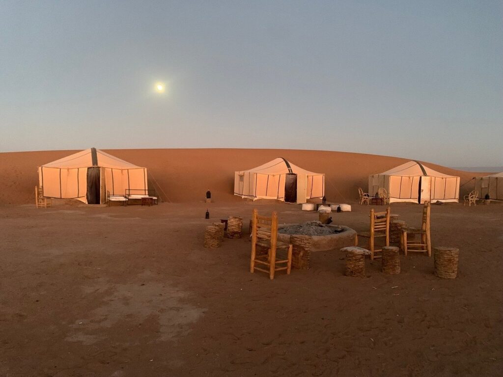 Campement de tentes berbères illuminées sous la pleine lune