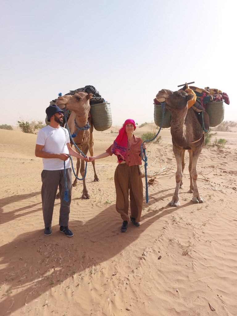 Couple tenant deux dromadaires dans le désert du Sahara au Maroc
