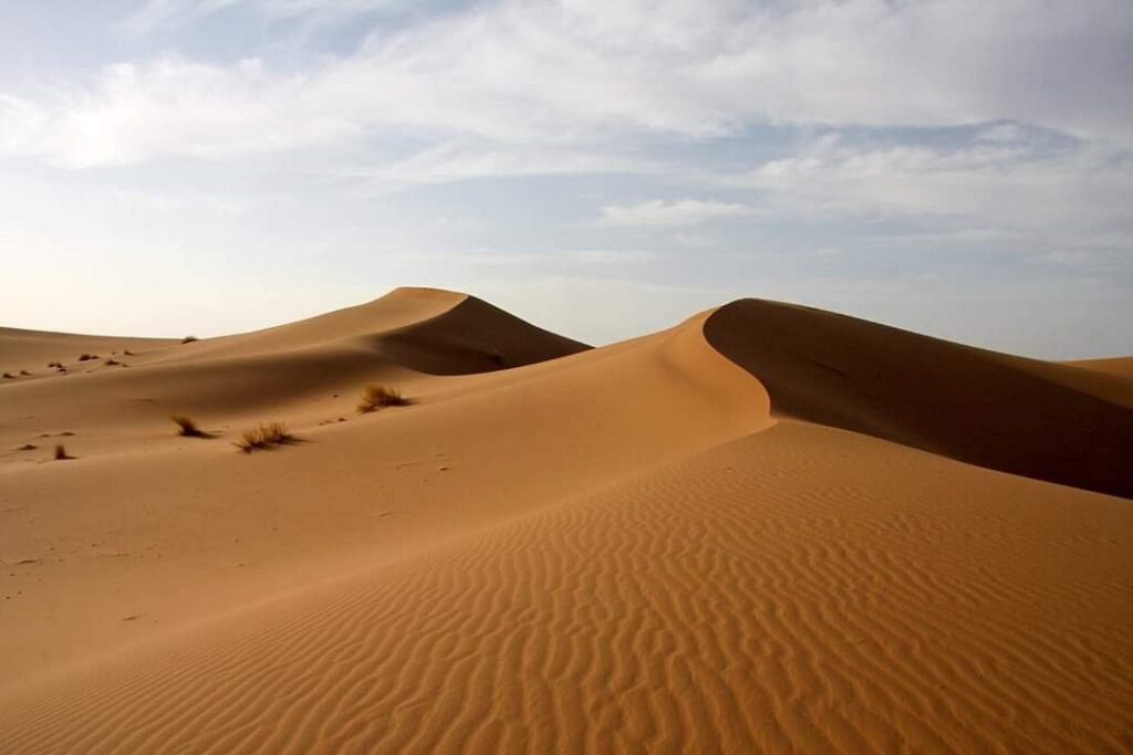 Dunes ondulées sous un ciel nuageux dans le désert marocain