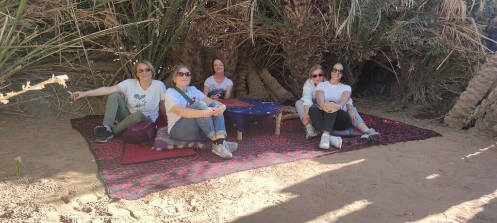 Groupe de femmes se reposant à l'ombre des palmiers dans une oasis du désert marocain