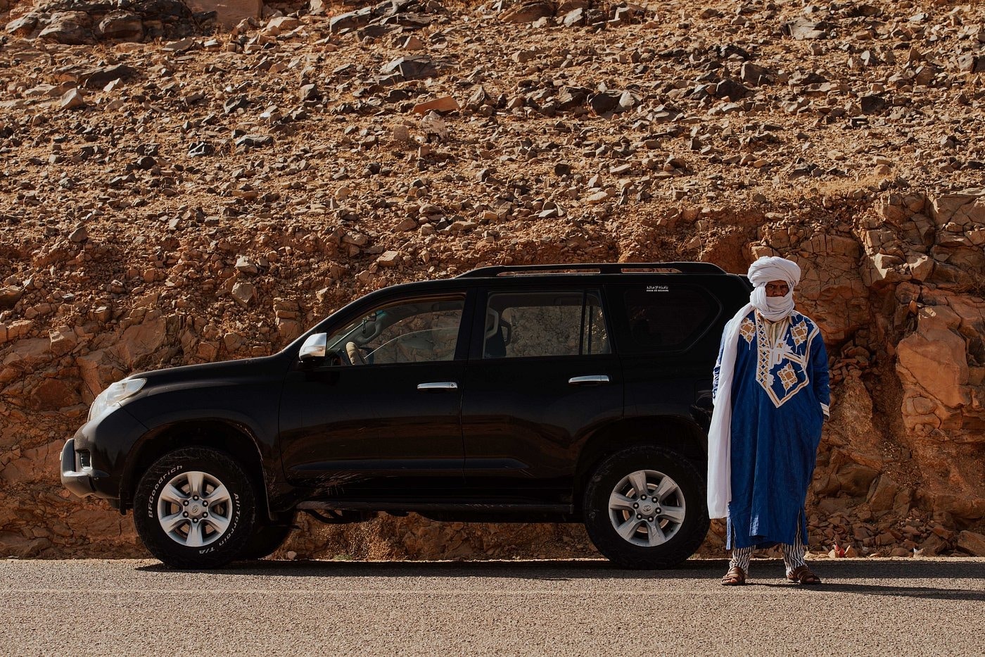 Guide berbère en tenue traditionnelle posant à côté d'un véhicule 4x4