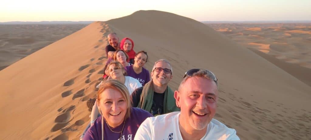 Selfie de groupe au sommet d'une dune du Sahara près de M'Hamid El Ghizlane au lever du soleil